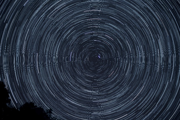 time laspe photo of stars swirling at night as earth rotates Time lapse astrophotograph showing stars swirling in the night sky as Earth rotates.